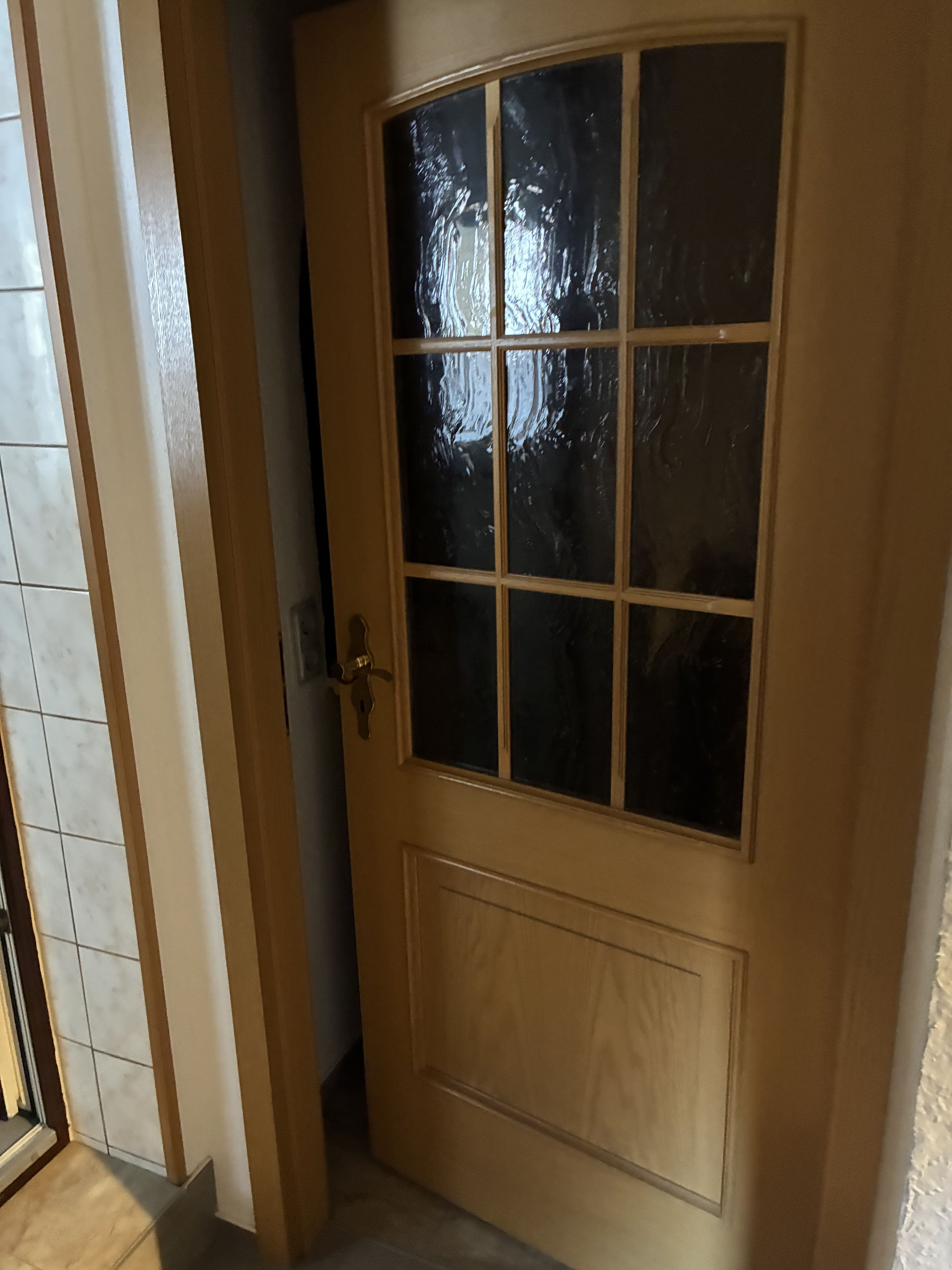 Une porte en bois avec un panneau de verre et une poignée en laiton.