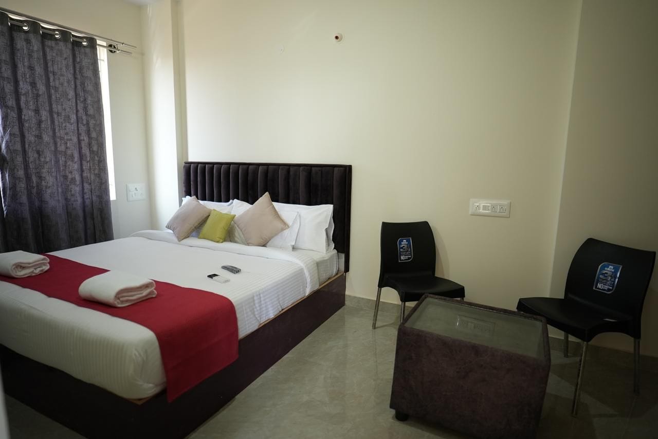 A hotel room with a bed, a desk, a chair, and a glass partition.