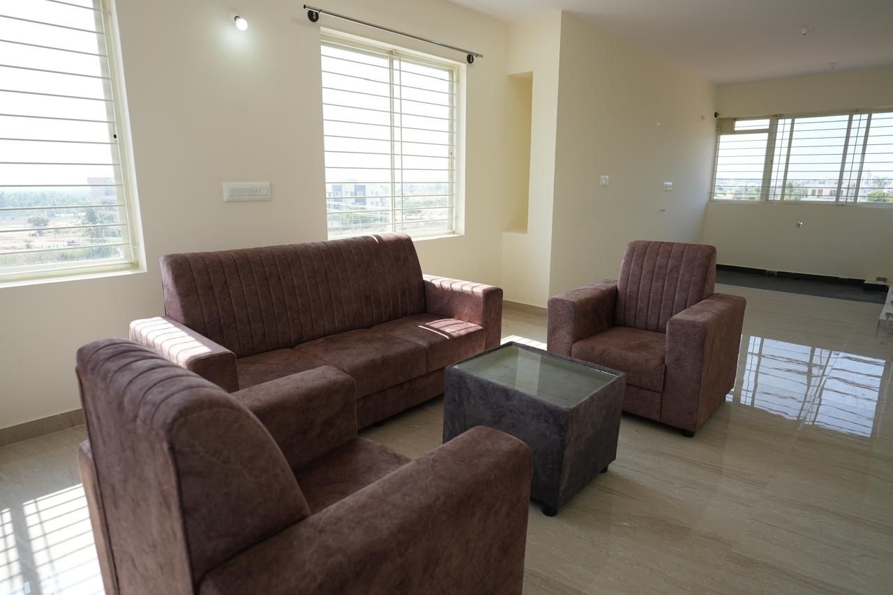 Ein Wohnzimmer mit einer Sofagarnitur, einem Couchtisch und einem Fenster mit Jalousien.