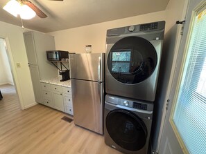 Una cocina compacta con refrigerador de acero inoxidable, horno empotrado y lavadora.