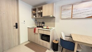 Cozinha compacta com micro-ondas, pia e um pequeno espaço de refeições com uma cadeira.