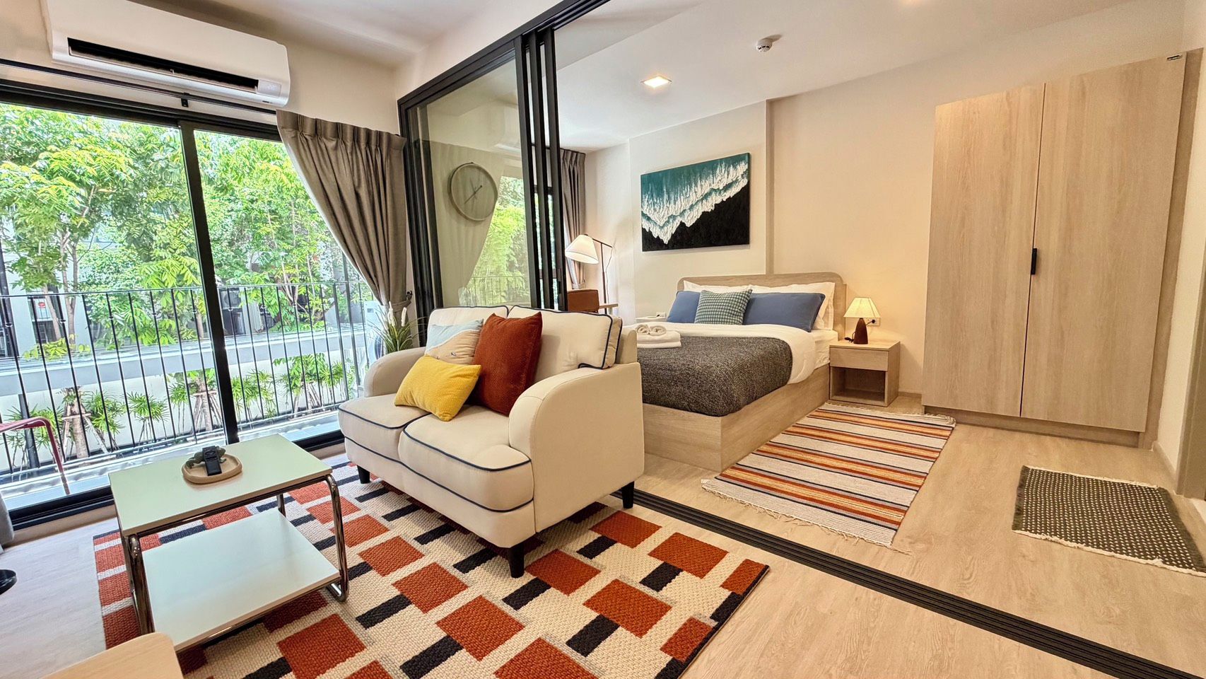Habitación de hotel moderna con sofá, cama, mesita, mesita de noche y armario.