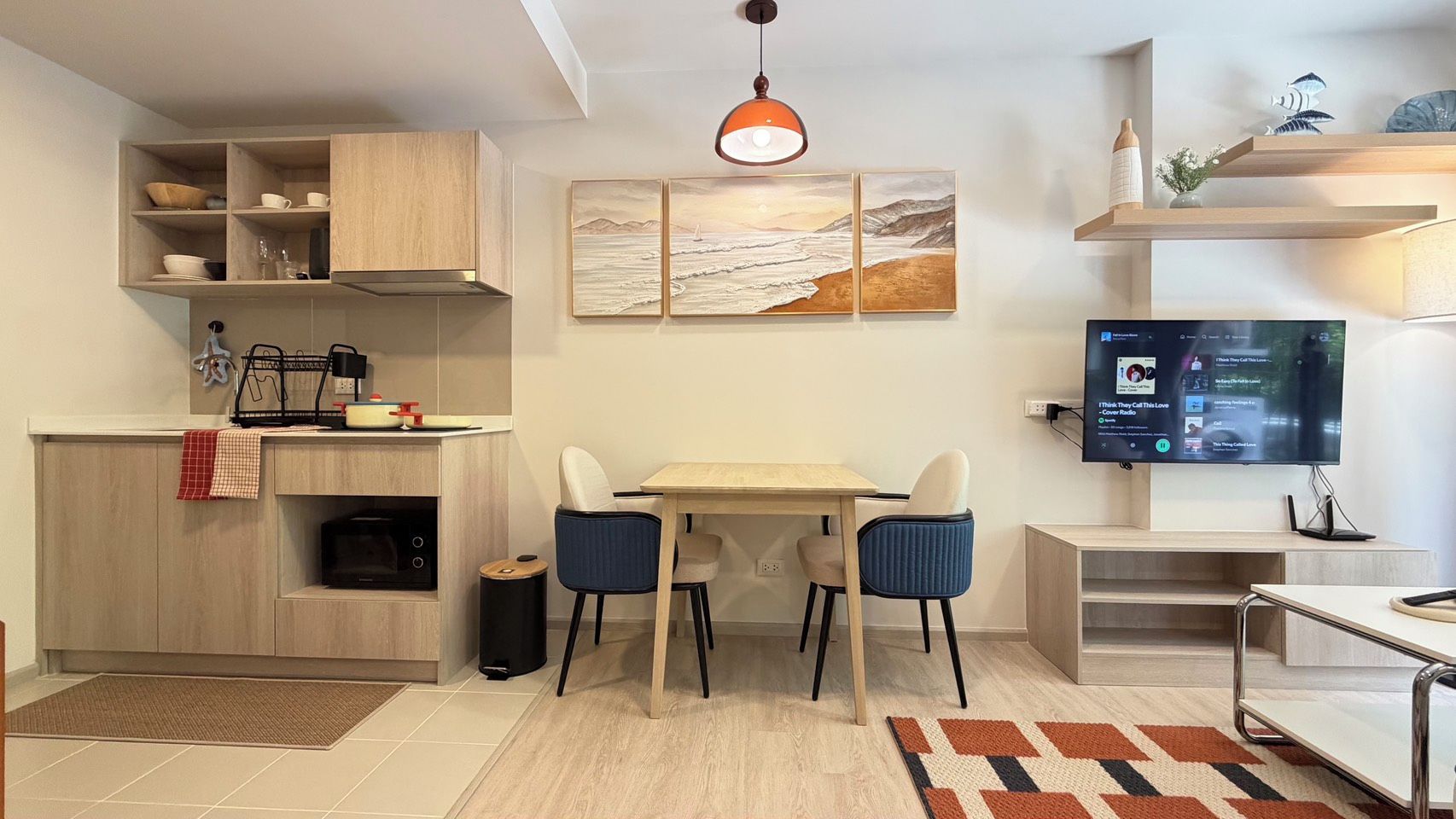 Cozinha moderna com área de refeições, televisão e obras de arte na parede.