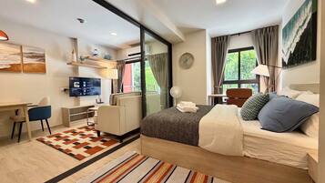 Quarto de hotel moderno com cama, escrivaninha, cadeira e uma grande janela.