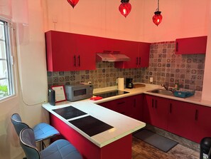 Una cucina moderna con mobili rossi, un forno a microonde, una macchina da caffè e un lavello.