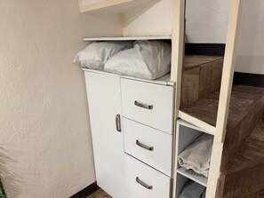 A white wardrobe with three drawers and a shelf, a wooden shelf unit, and a white wall. - Loft (double-height) on the boardwalk, half a block from the beach (Puerto Vallarta)