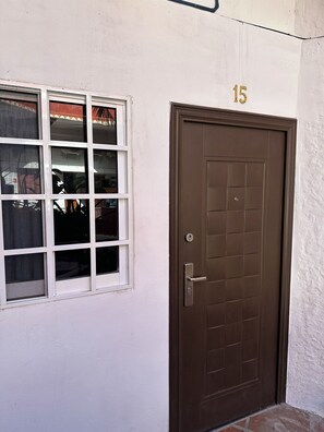 A brown door with a window to the left, a number '15' above the door, and a small step leading up to the door. - Loft (double-height) on the boardwalk, half a block from the beach (Puerto Vallarta)