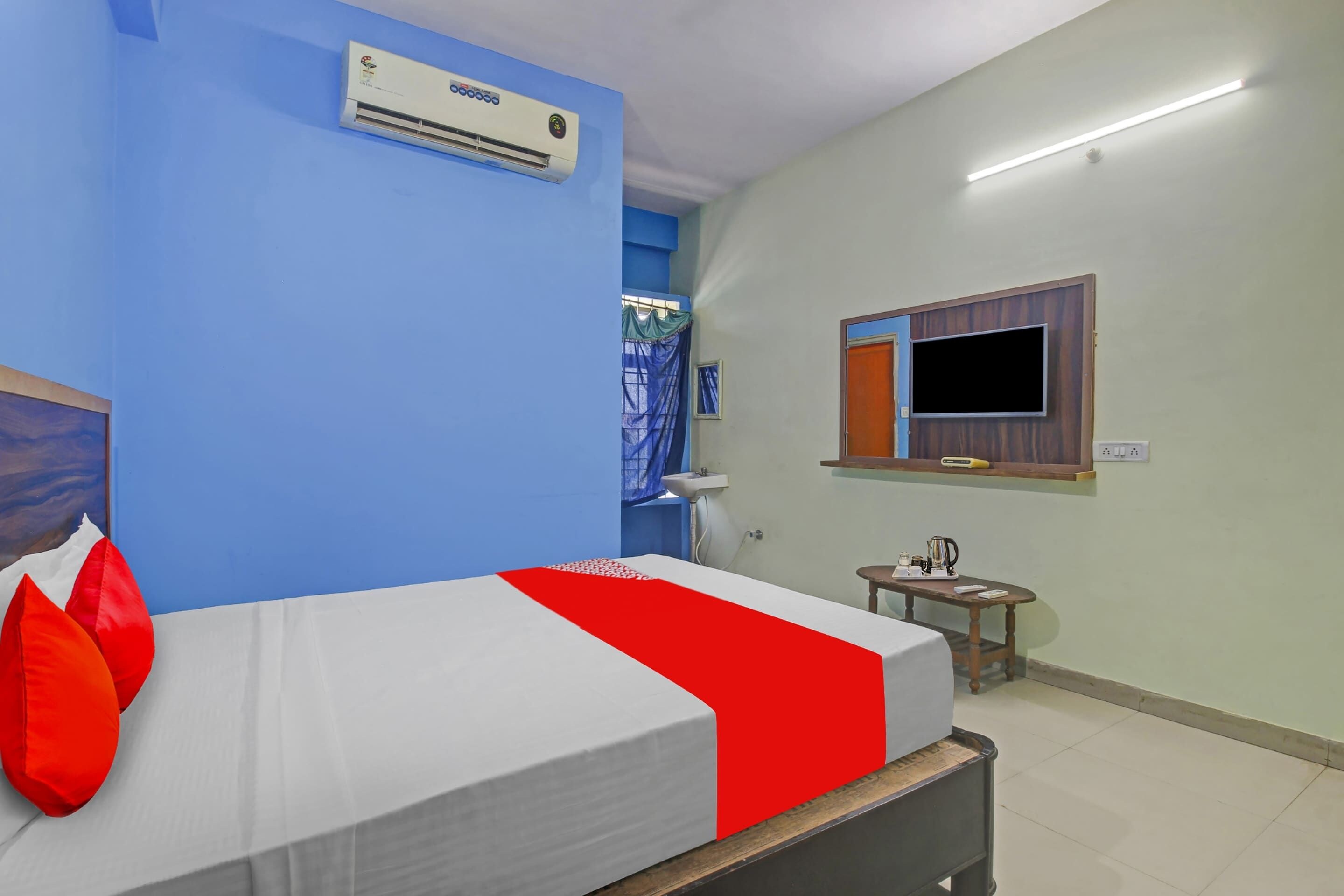 A hotel room with a bed, a television mounted on the wall, and a window with curtains.
