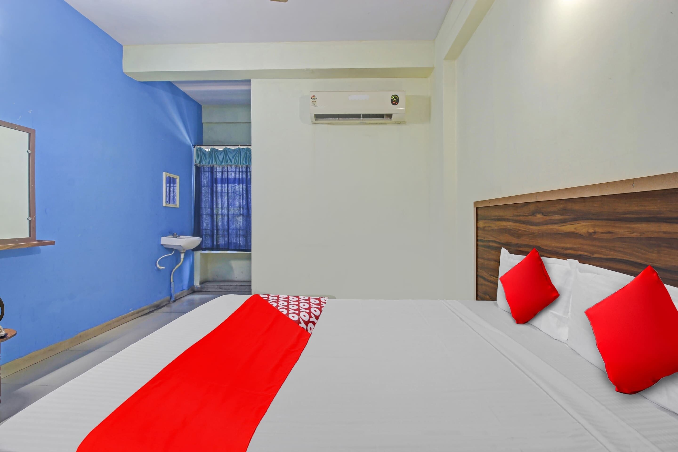 Een hotelkamer met een bed, een raam, een wastafel en een airconditioning.