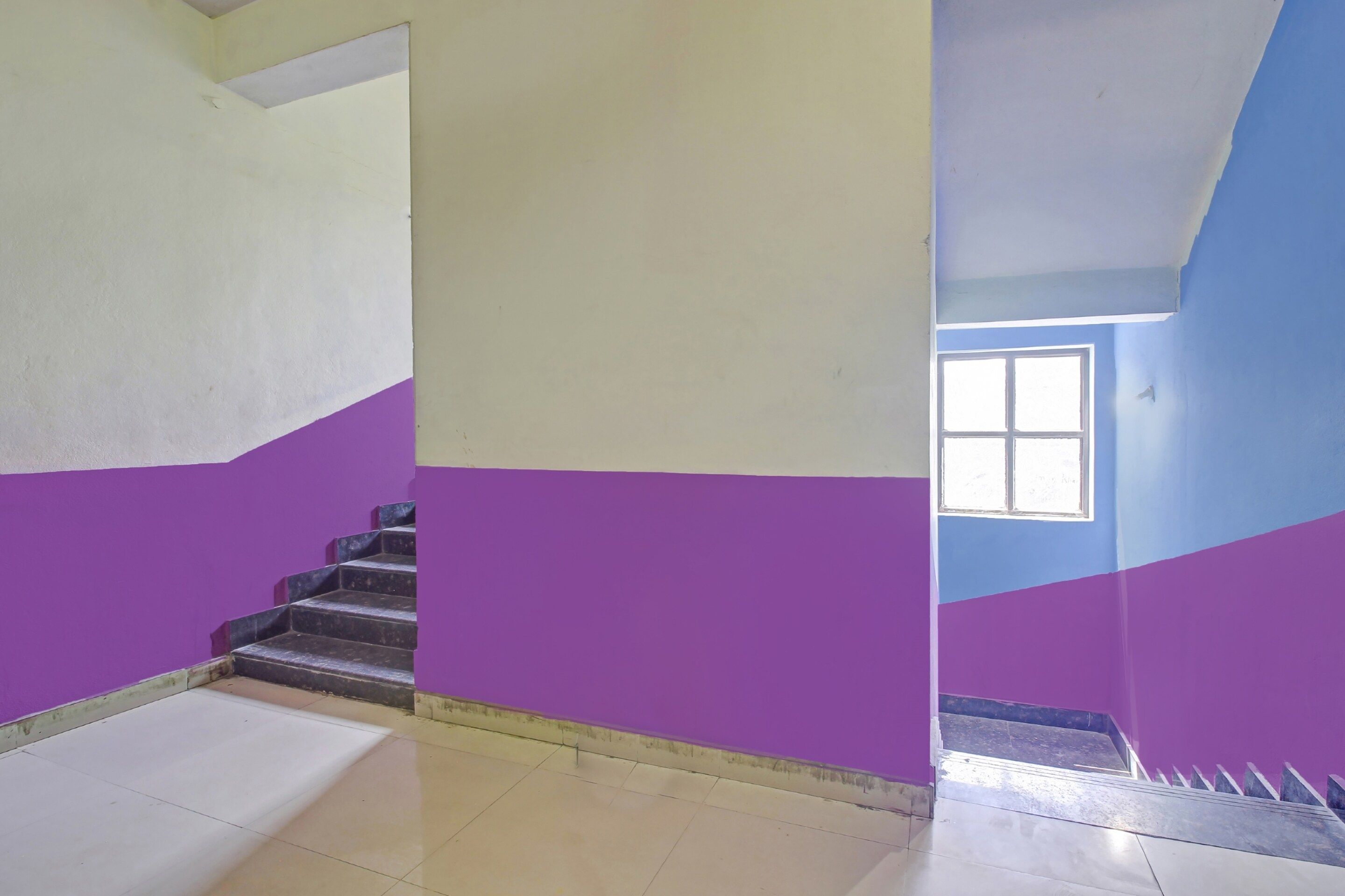 Eine Treppe mit abwechselnd weißen und violetten Wänden, die zu einem Zimmer mit einem Fenster führt.