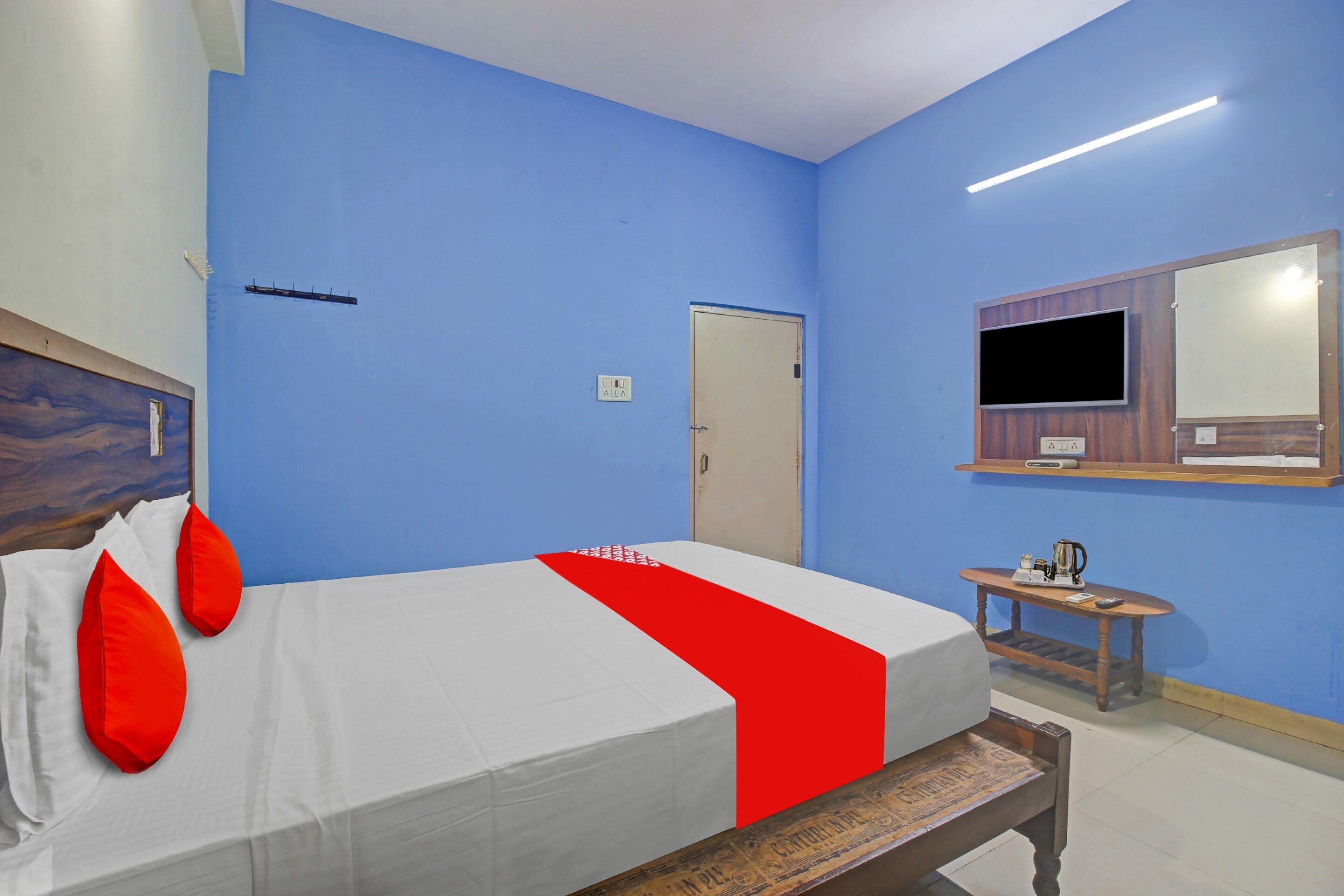 A hotel room with a bed, a bedside table, a mirror, and a door.