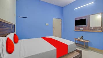 A hotel room with a bed, a bedside table, a mirror, and a door.