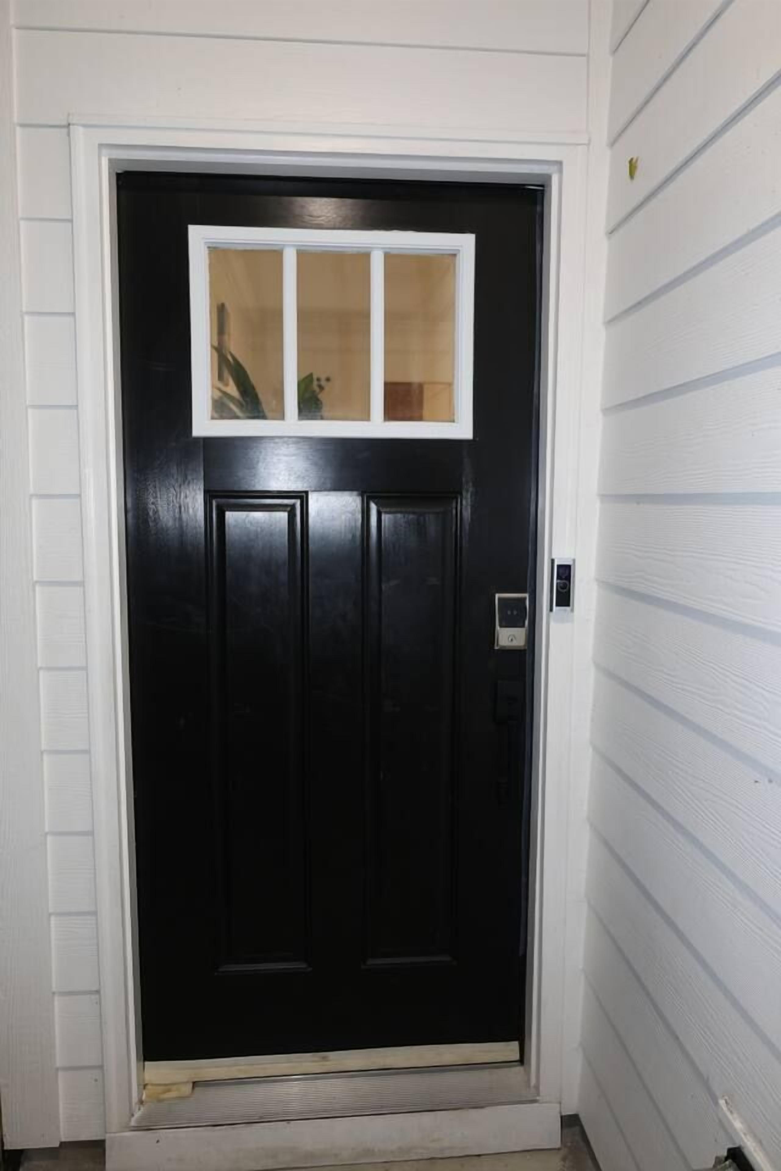 A black door with a white-framed window above it.