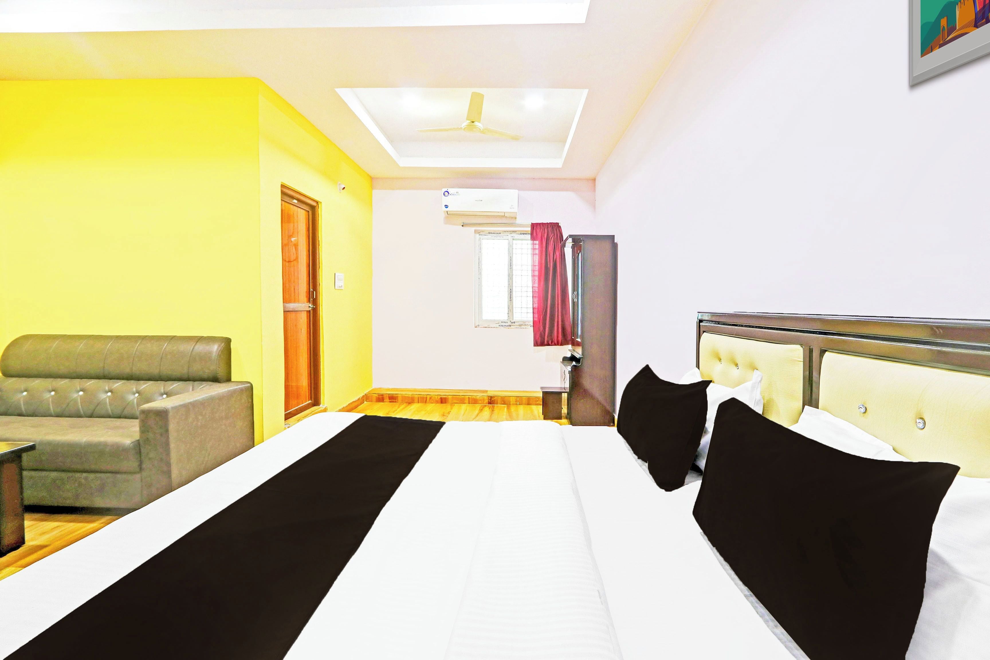 A hotel room with a bed, a sofa, a desk, and a window with curtains.