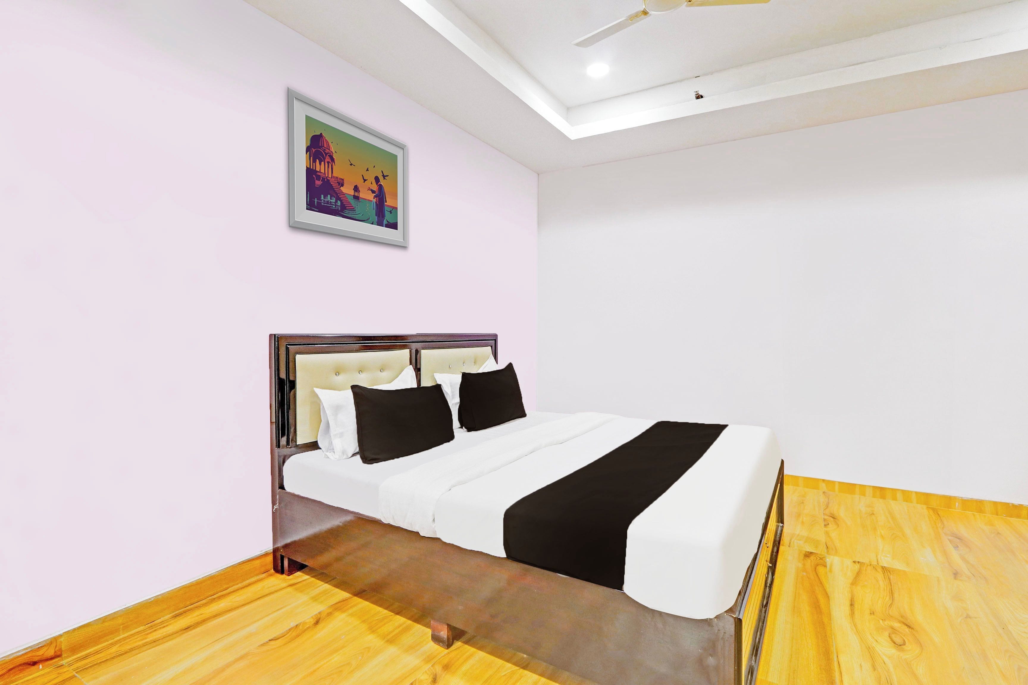 Una habitación de hotel con una cama, un ventilador de techo y un cuadro en la pared.