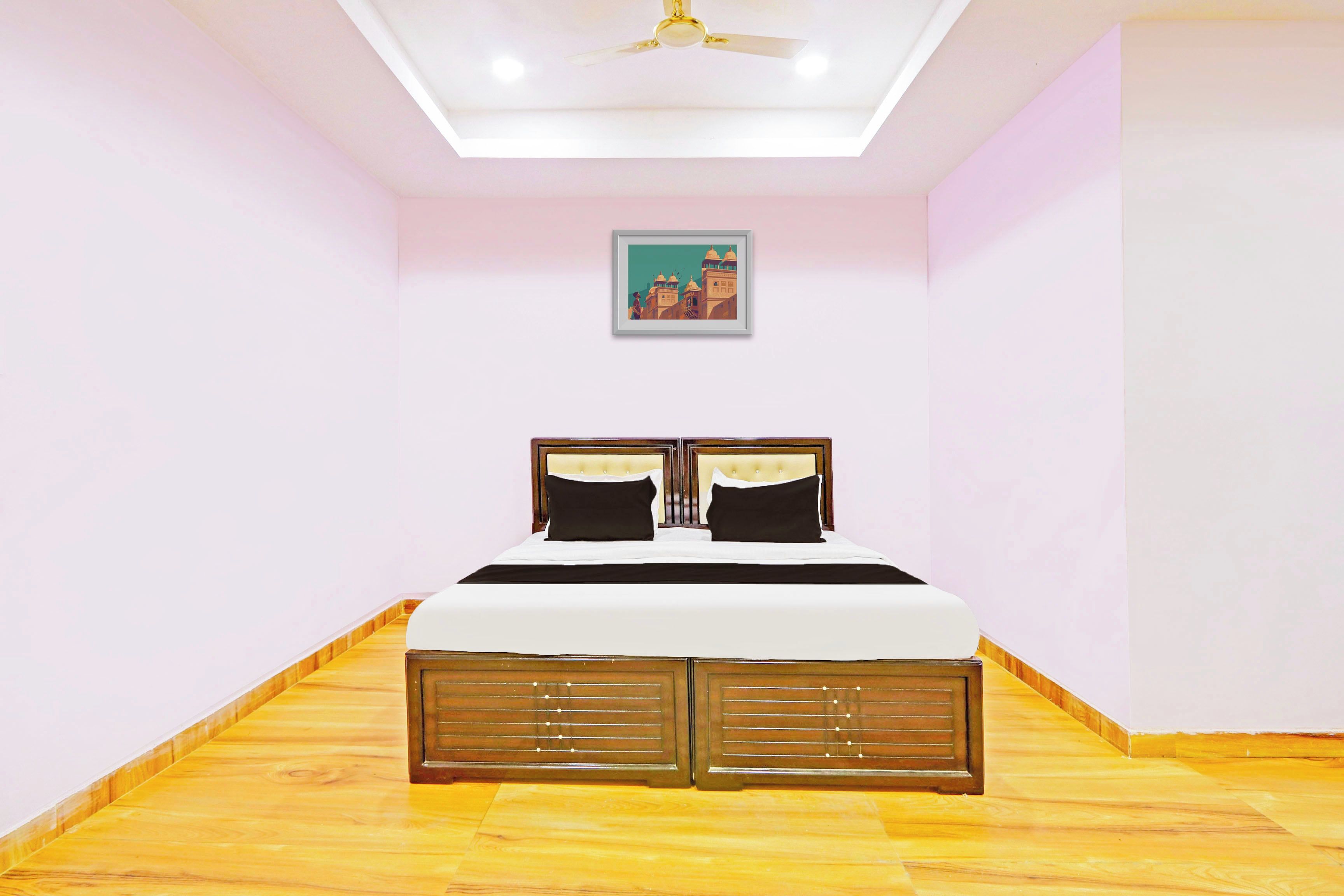 Ein Schlafzimmer mit einem Bett, einem Deckenventilator, einem gerahmten Bild an der Wand und Holzböden.