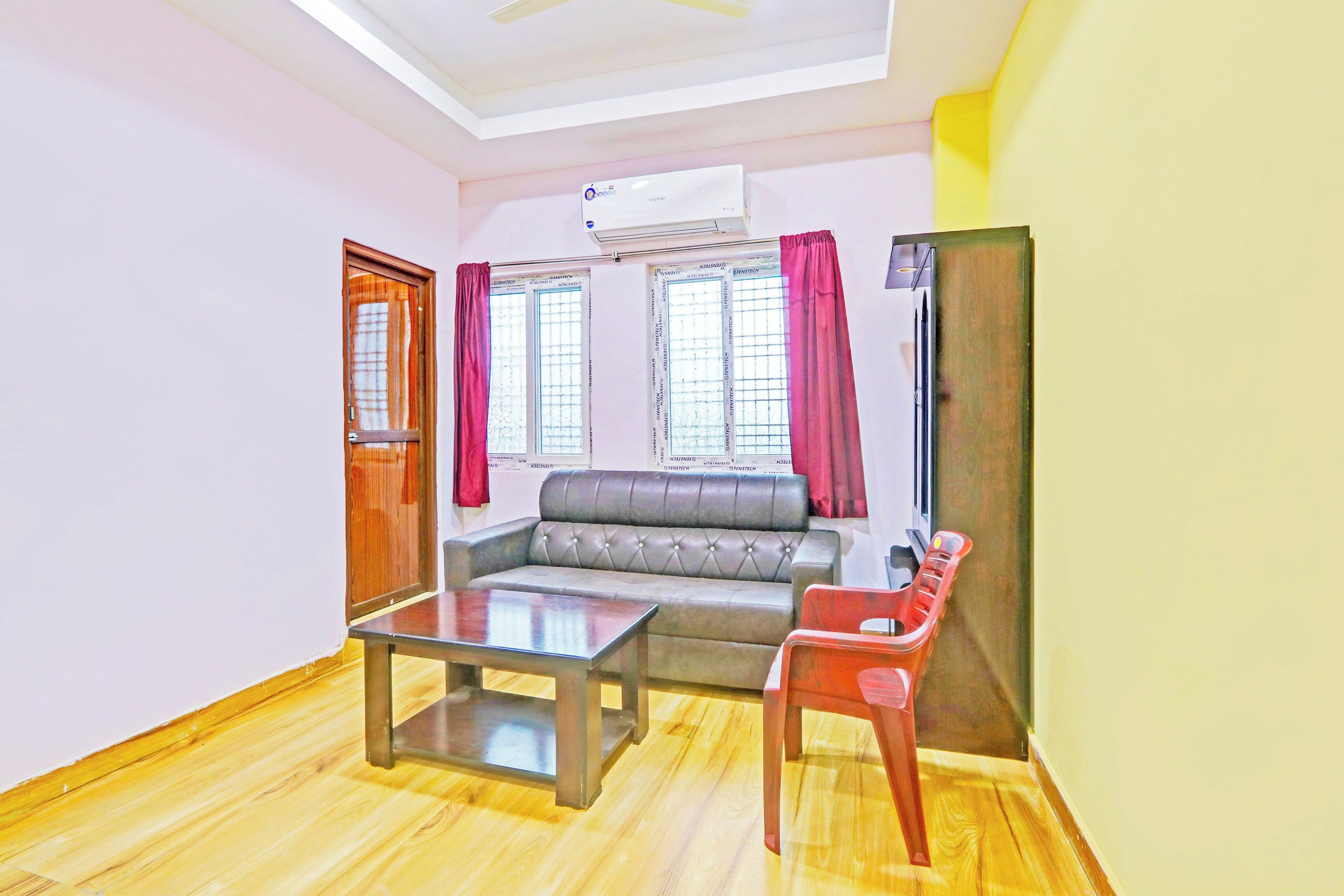 A living room with a sofa, a coffee table, a red chair, and a television.