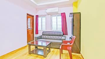 A living room with a sofa, a coffee table, a red chair, and a television.
