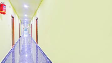 A long, narrow hallway with a fire extinguisher mounted on the wall, a ceiling with recessed lighting, and a door at the end.