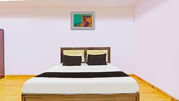 Een slaapkamer met een bed, een hoofdeinde, een schilderij aan de muur en houten vloeren.