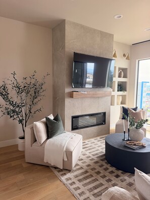 A modern living room with a flat-screen TV mounted on a wall, a beige sofa, a round coffee table, and a potted plant. - Perfect 3-bedroom townhome in gorgeous Vancouver with City Views and EV charger (Vancouver)