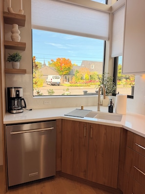A modern kitchen with a built-in dishwasher, a coffee maker, and a window with a view of a residential street. - Perfect 3-bedroom townhome in gorgeous Vancouver with City Views and EV charger (Vancouver)