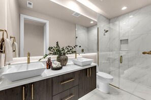 Een moderne badkamer met een grote spiegel, twee wastafels, een douche en donkere houten kastjes.