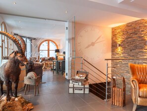 A modern interior with a stone wall, a large clock, and a staircase. - Arcade Appartement/Fewo 4-Bettwohnung Nr. 115C02 by Interhome (Saas-Fee)