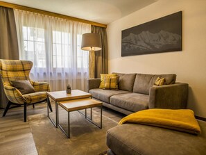 Ein Wohnzimmer mit einer Couch, einem Sessel, einem Couchtisch und einer Lampe.