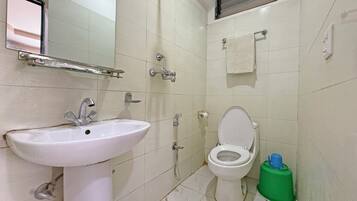 Un baño con lavamanos, inodoro, ducha y espejo.