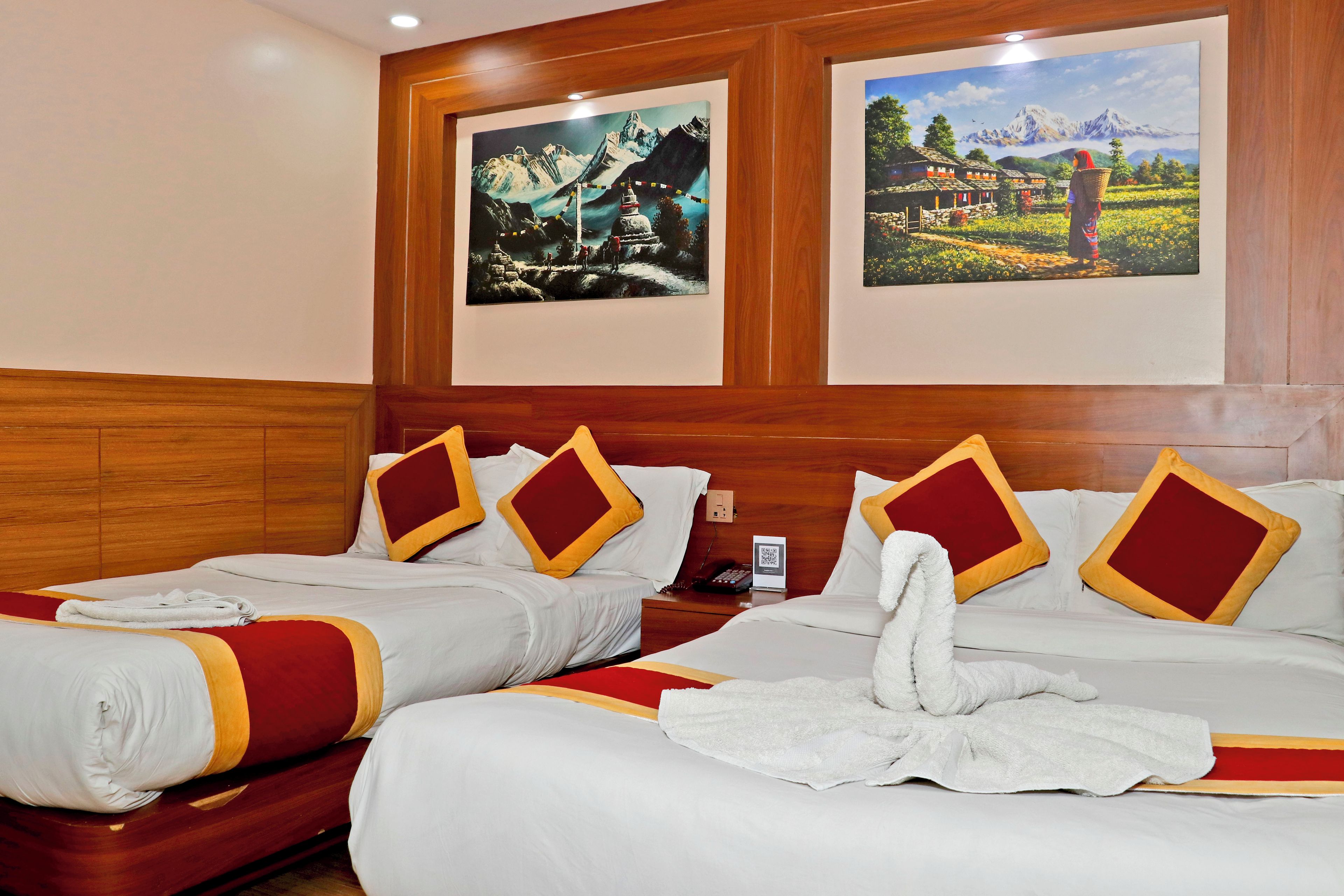 Habitación de hotel con dos camas, cabecero de madera y dos cuadros en la pared.