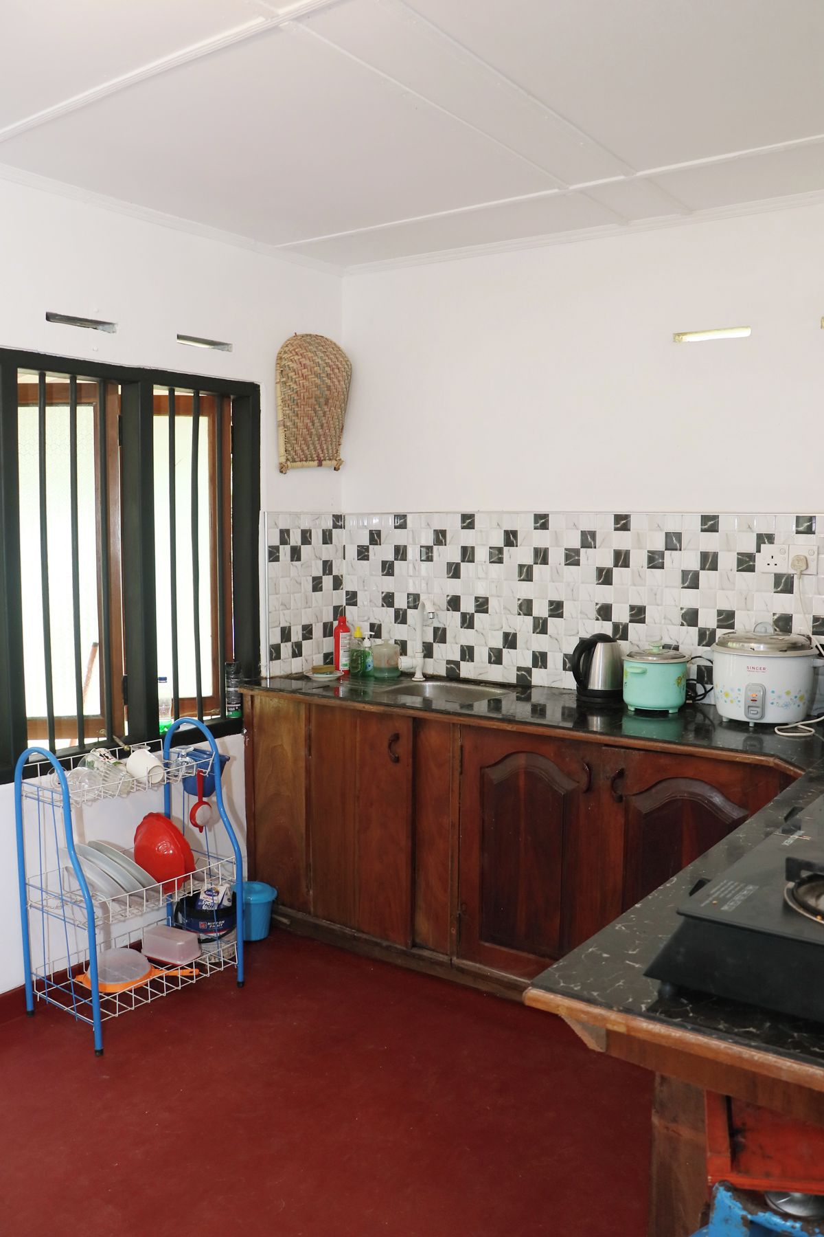 A kitchen with a tiled backsplash, a stove, a sink, and a dish rack.