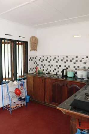 A kitchen with a tiled backsplash, a stove, a sink, and a dish rack.