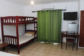 A bunk bed with a desk and chair, a television, and a curtain.