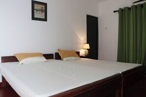 A double bed with white bedding and two pillows, a bedside table with a lamp, a framed picture on the wall, and a green curtain. - Breathtaking Mountain & Rainforest Views / Cozy 2- Bed HilltopBungalow (SP)