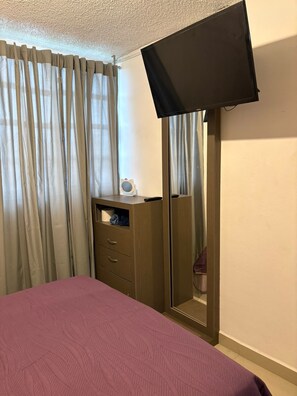 A bedroom with a bed, a dresser, a mirror, and a television mounted on the wall. - Penthouse ideal for work groups or family vacations, in a great location (Cuautitlán Izcalli)