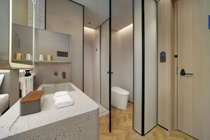 Een moderne badkamer met een douche, toilet en een wastafel met spiegel.