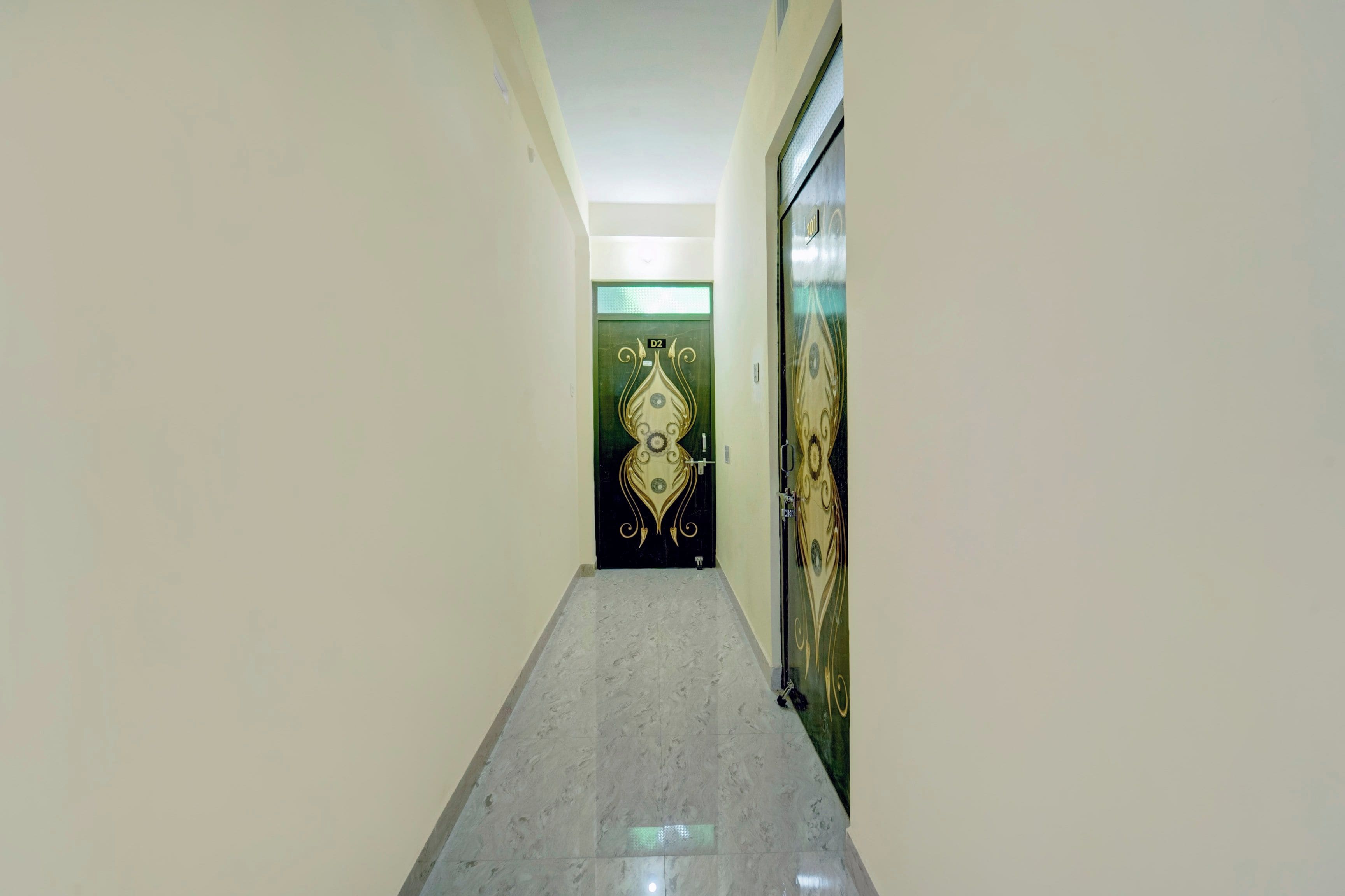 Un pasillo con piso de mármol que conduce a una puerta con diseño decorativo.