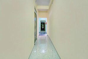 Un pasillo con piso de baldosas que conduce a una puerta con un panel de vidrio decorativo.