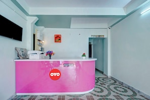 A reception area with a pink counter, a Sony TV mounted on the wall, and a reception sign. - Hotel O City View (Patna)