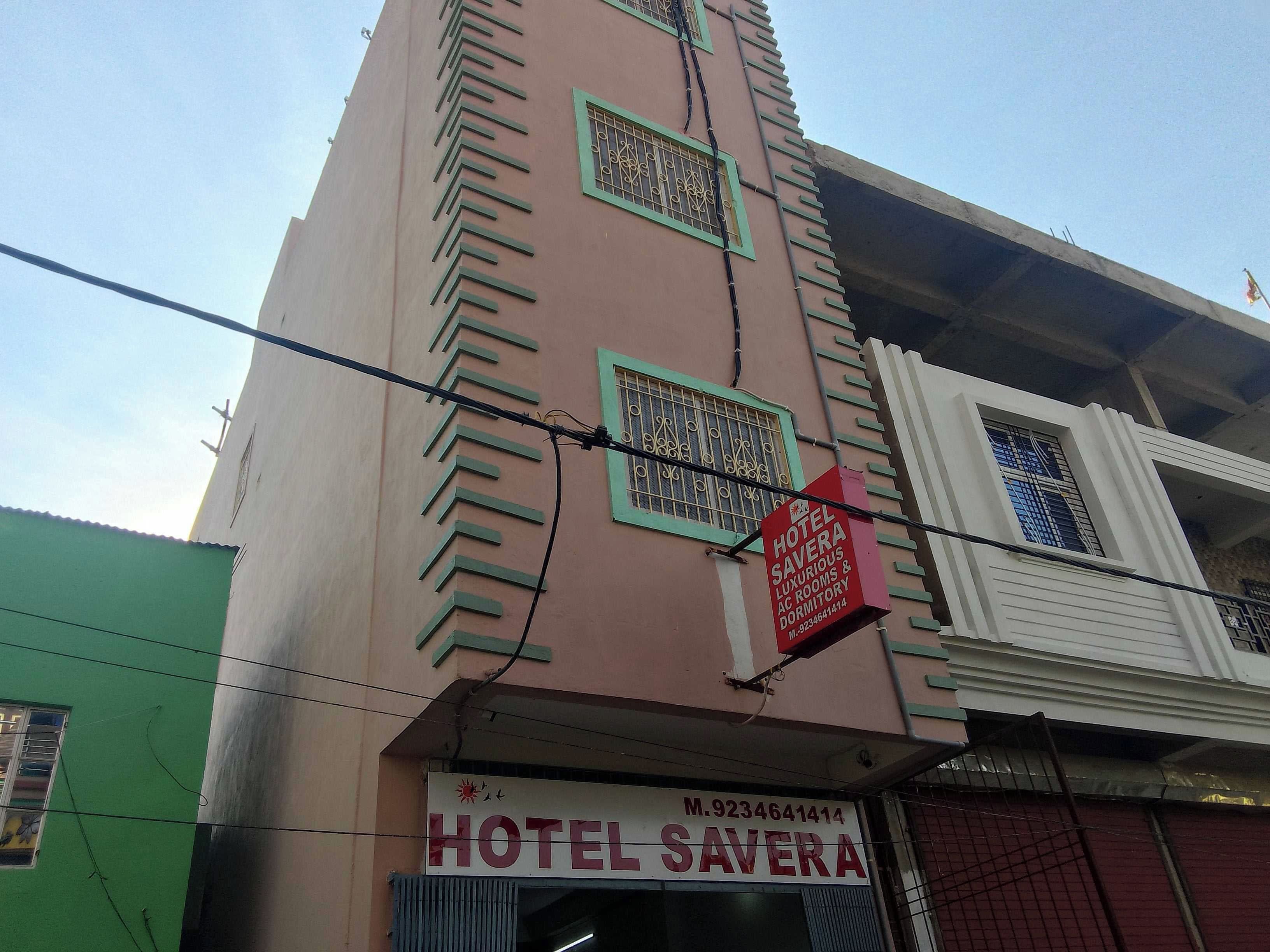 Un hotel llamado 'HOTEL SAVERA' con un letrero que muestra el nombre y el número de contacto.