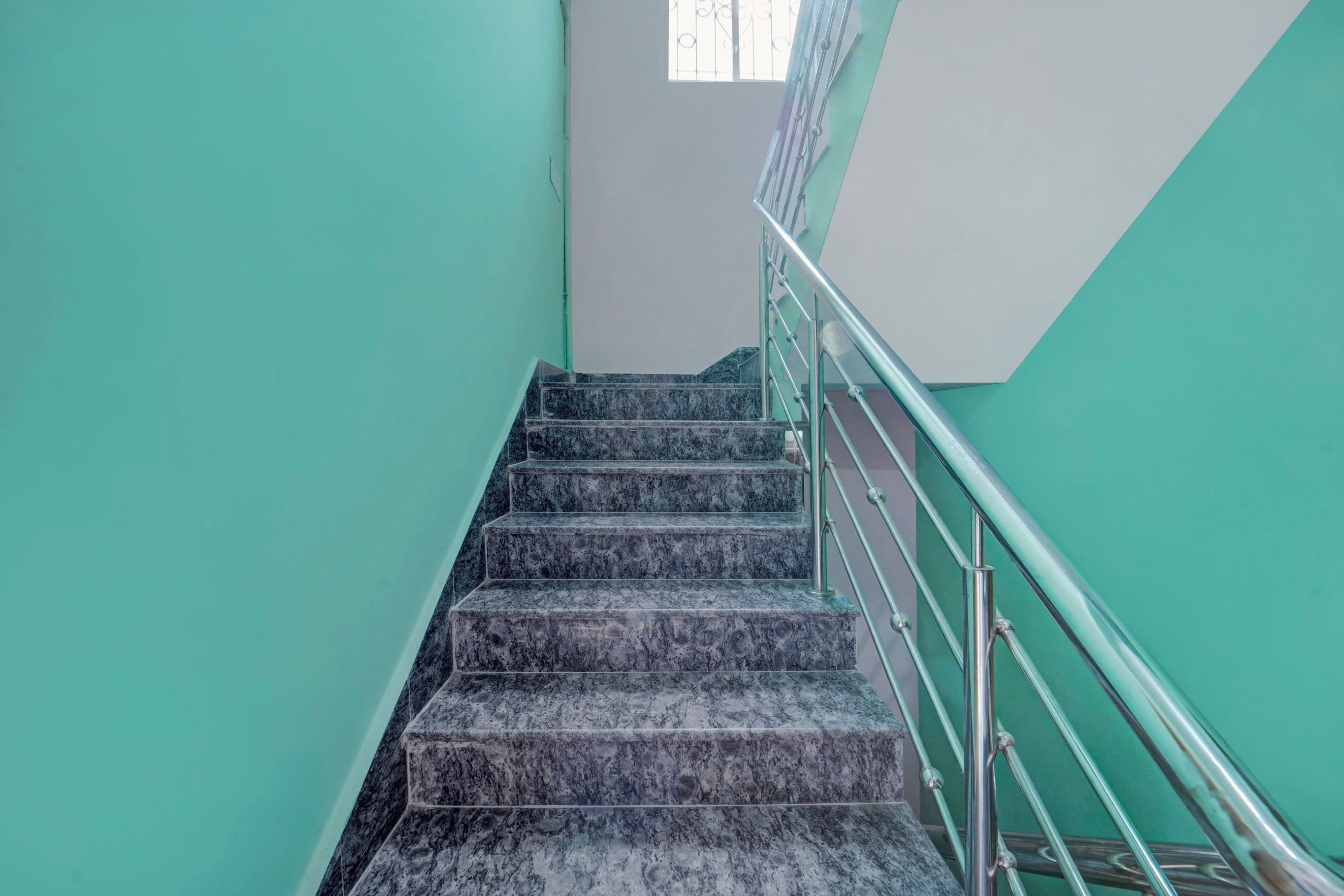 Una escalera con barandilla de metal y peldaños de mármol.
