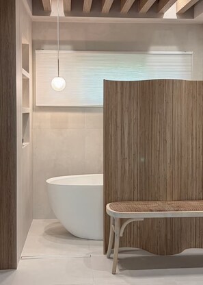 Ein modernes Badezimmer mit einer freistehenden Badewanne, einer Sitzbank und einer hängenden Leuchte.