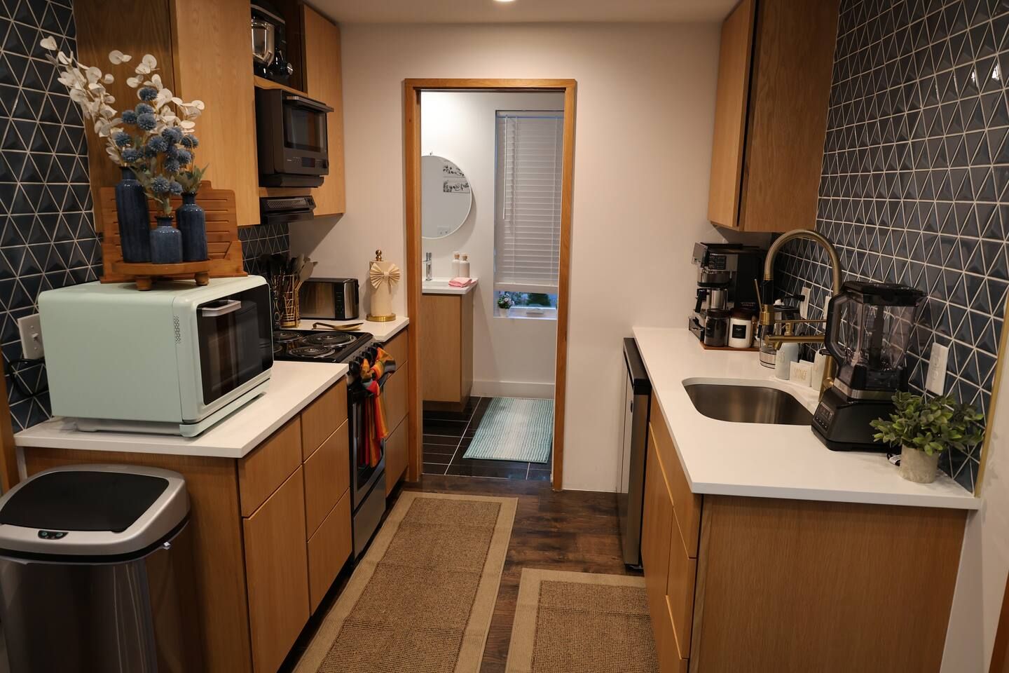 Una cocina compacta con armarios de madera, un microondas, una estufa y un lavabo.