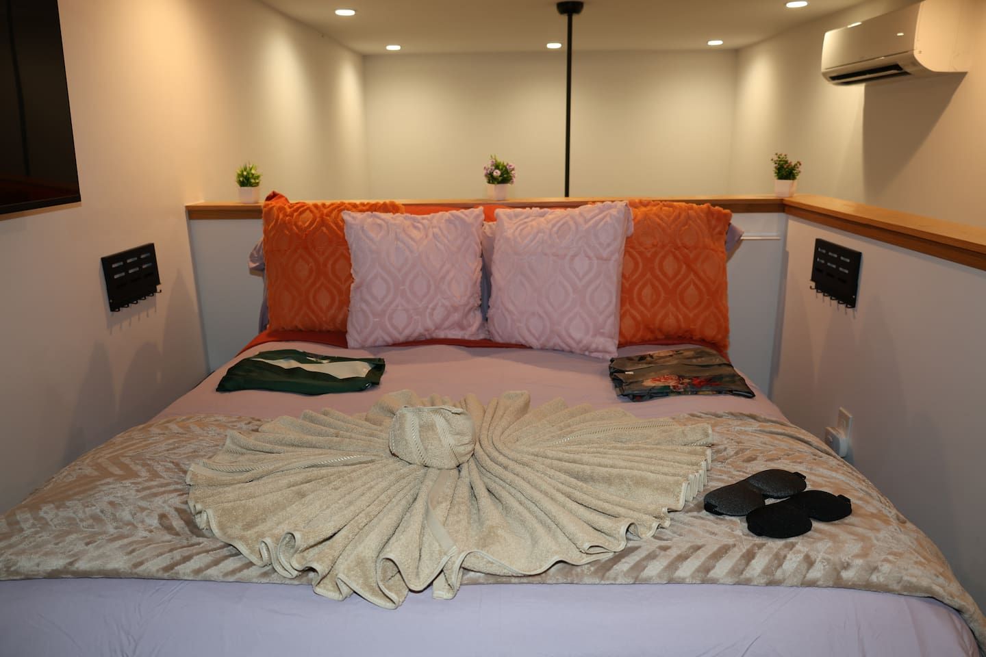 Una habitación de hotel con una cama, almohadas, una toalla y una planta pequeña.