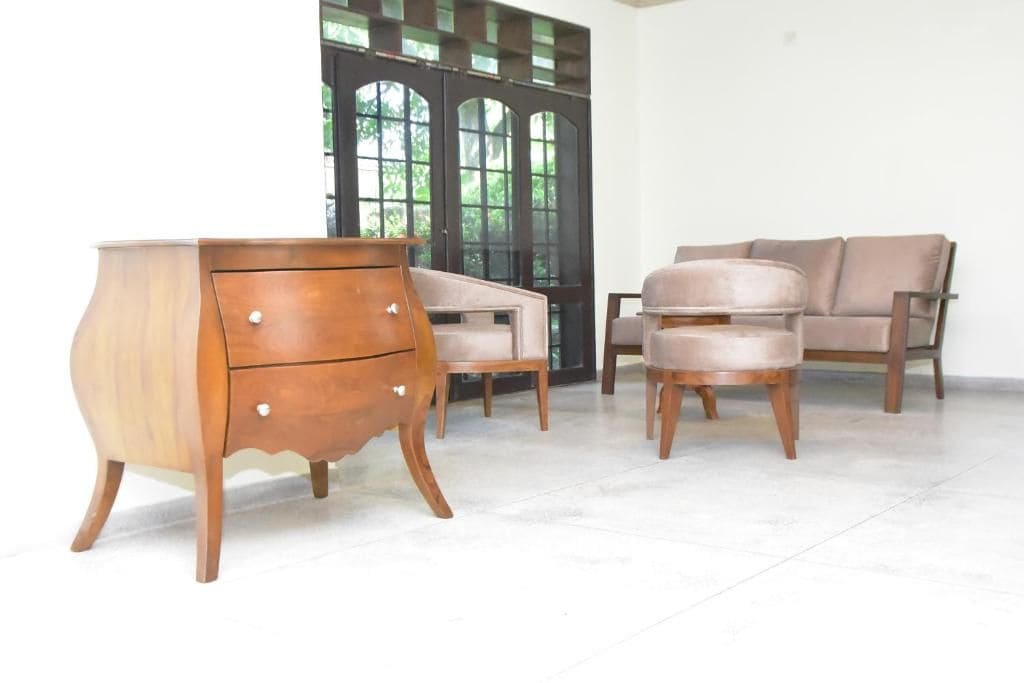 A room with a wooden dresser, two armchairs, and a sofa.