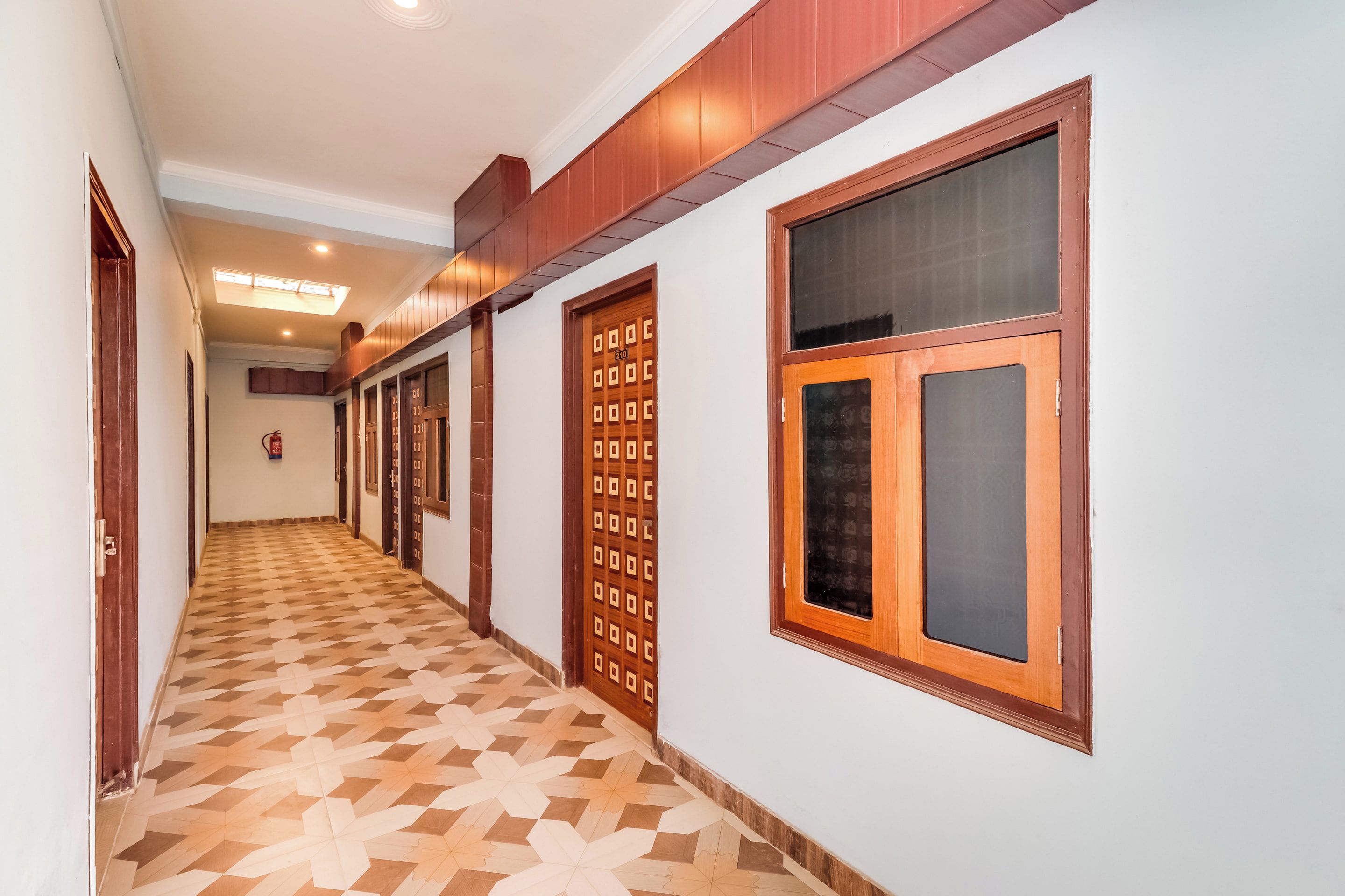 A hallway with patterned flooring, wooden doors, and a fire extinguisher.