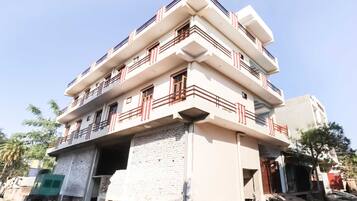 A multi-story building with balconies, a brick foundation, and a clear sky.