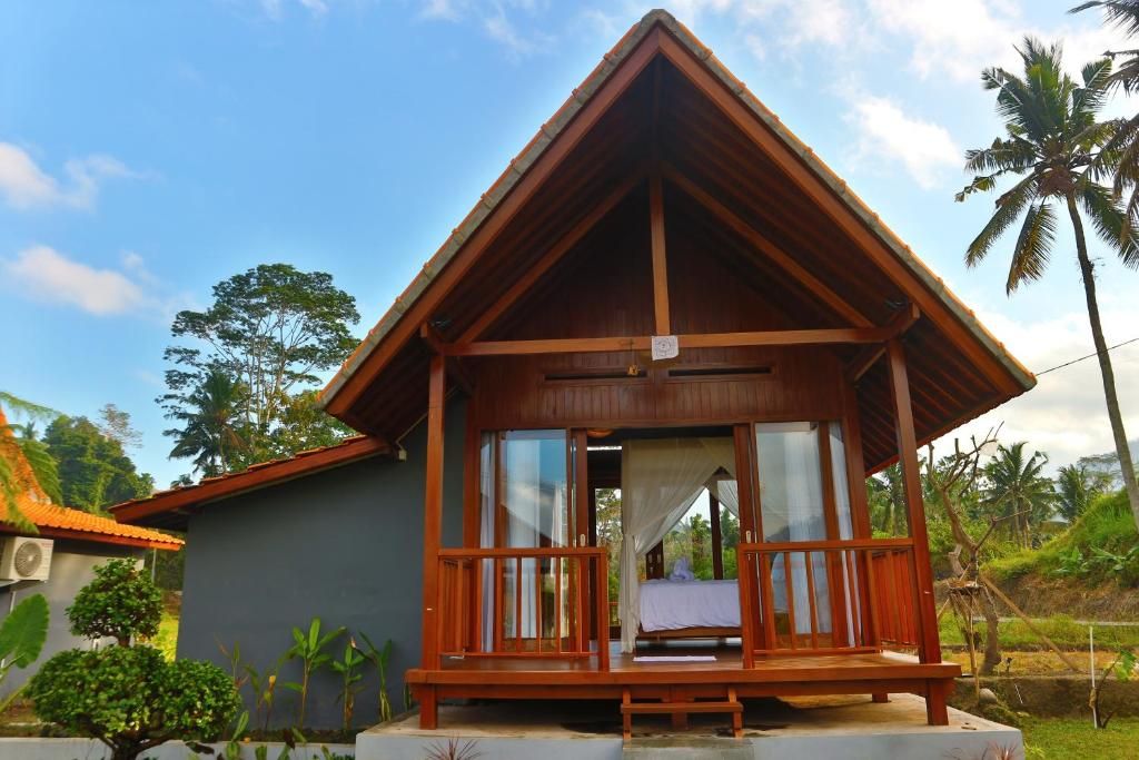 Una cabaña de madera con balcón, ventanas amplias y vista a palmeras.