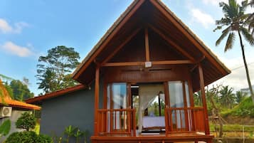 Una cabaña de madera con balcón, ventanas amplias y vista a palmeras.